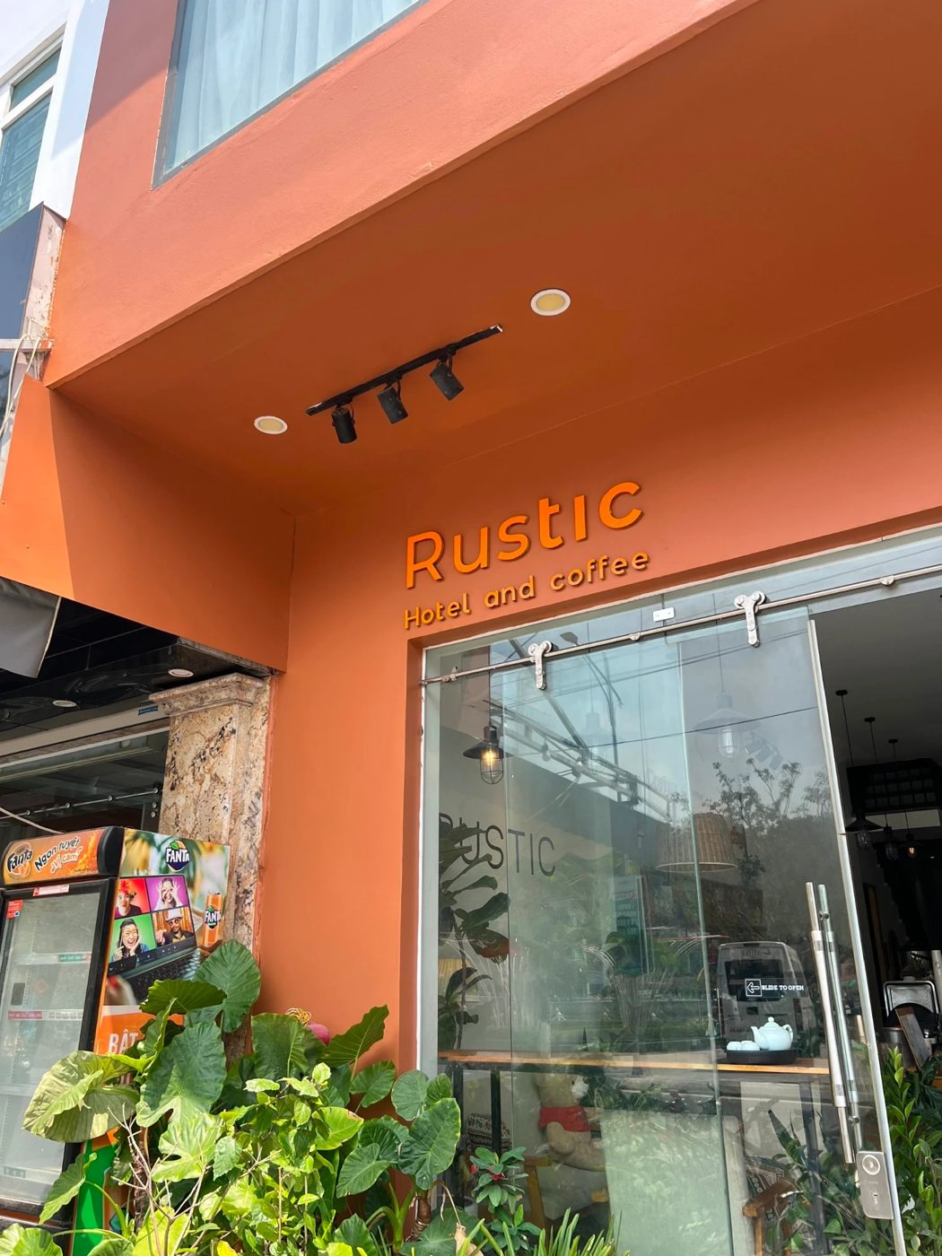The orange front of Rustic Hotel and Coffee on quiet Tung Dinh street, with the café on the ground floor
